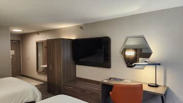 A hotel room with a bed, a desk, a chair, a wardrobe, a television, and a mirror.