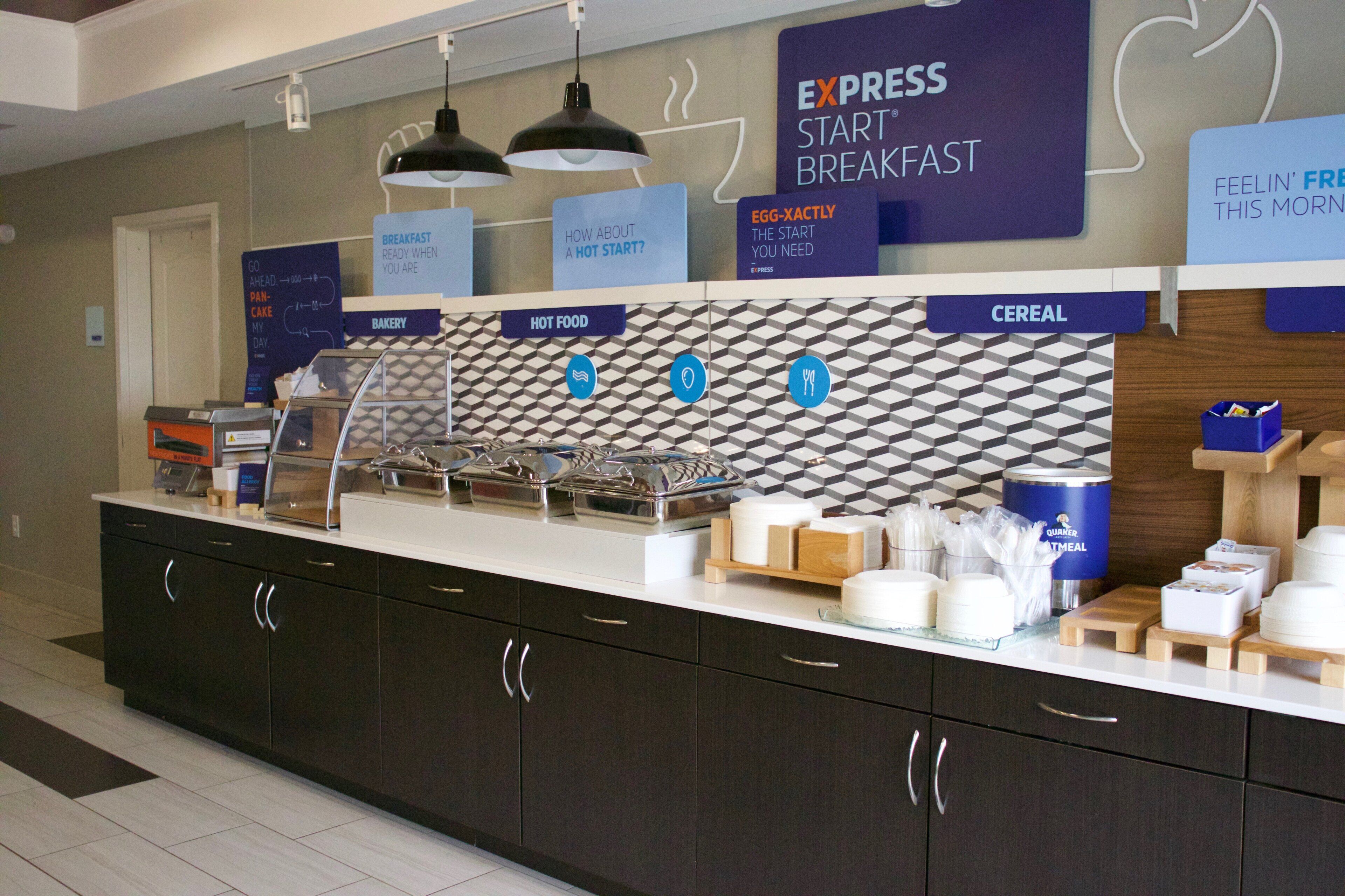A breakfast buffet area with labeled sections for bakery, hot food, and cereal.