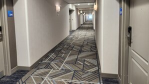 A hotel hallway with patterned carpet, white walls, and doors numbered 224 and 225. - Holiday Inn Express Hotel & Suites Crawfordsville by IHG (Crawfordsville)