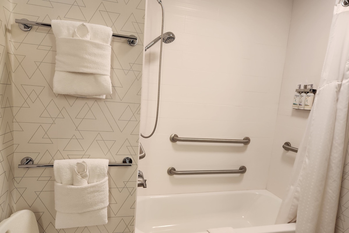 A modern bathroom with a shower, a bathtub, and two towel bars.
