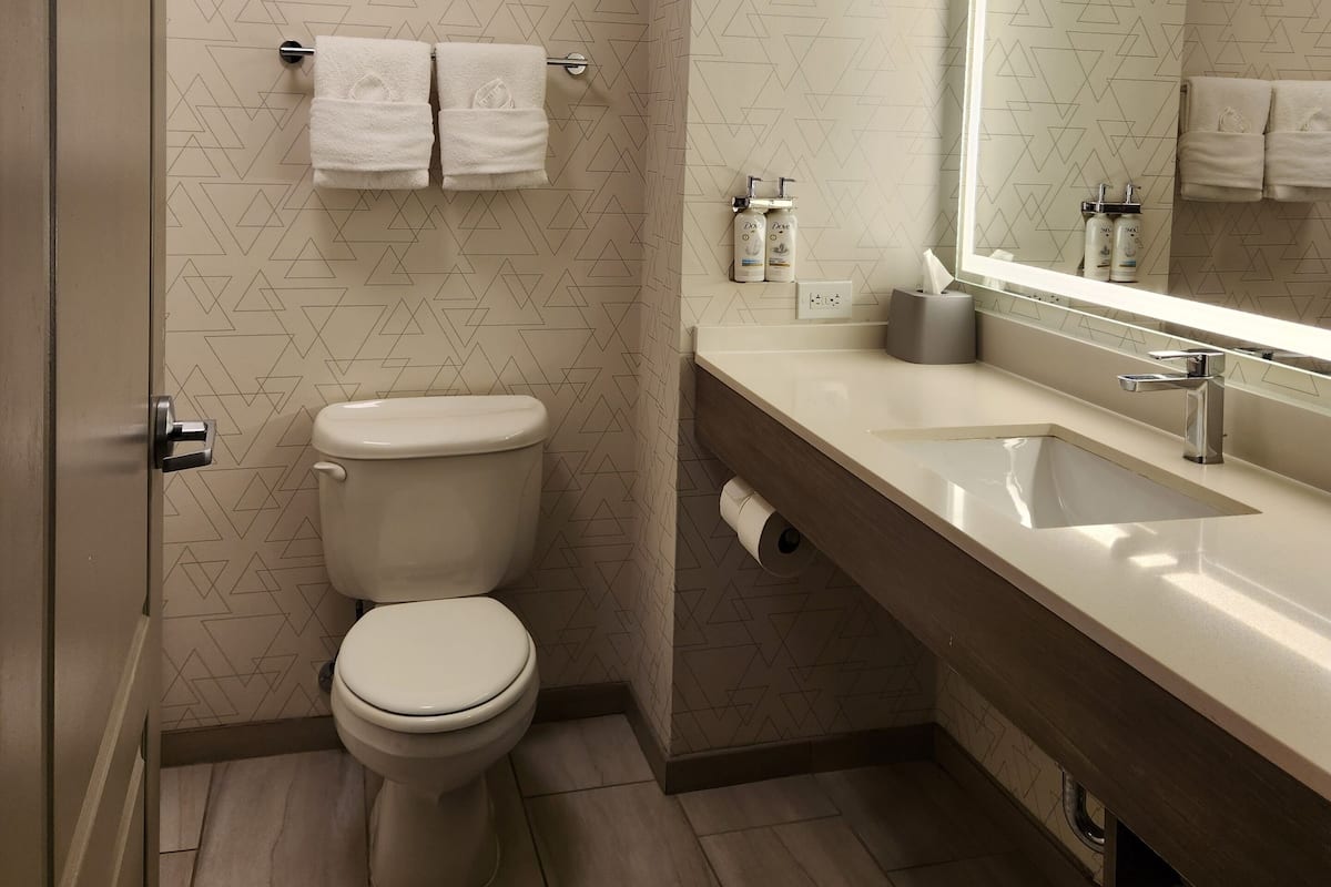 A modern bathroom with a toilet, a sink with a mirror, and patterned wall tiles.