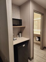 Una kitchenette compacta con microondas, un refrigerador pequeño y un lavamanos.