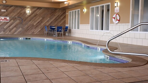 An indoor swimming pool with a no diving sign, blue chairs, and a lifebuoy on the wall. - Holiday Inn Express Hotel & Suites Crawfordsville by IHG (Crawfordsville)