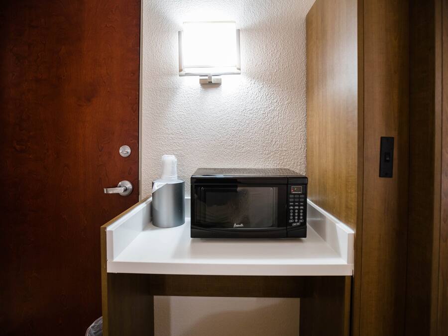 A microwave on a white countertop in a room with a wooden door and a textured wall.