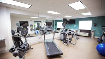 Un gimnasio con cintas de correr, elípticas y pelotas de ejercicio.