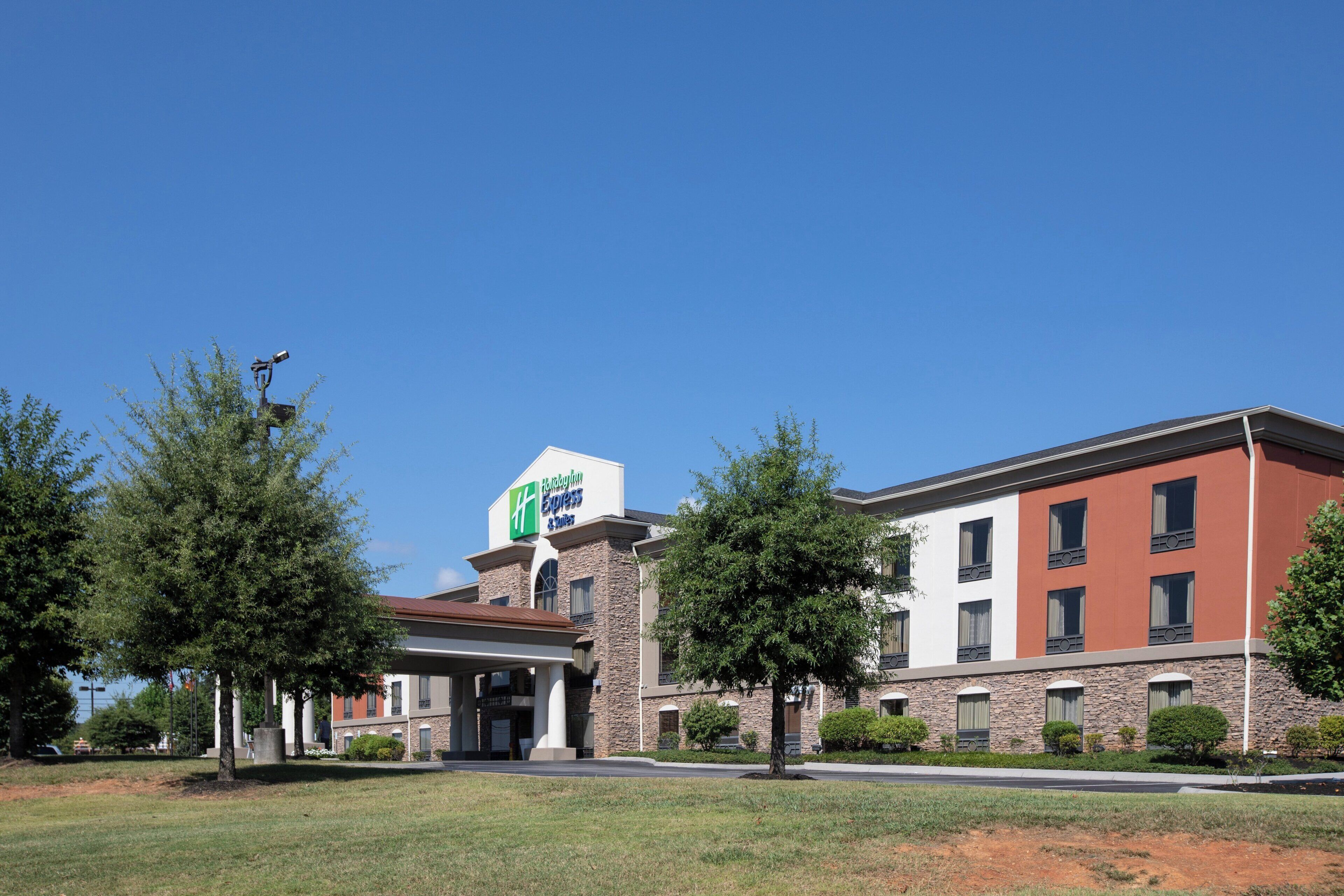 Un bâtiment de l’hôtel Holiday Inn Express avec une façade en pierre, de nombreuses fenêtres et un ciel bleu clair.
