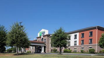 Un bâtiment de l’hôtel Holiday Inn Express avec une façade en pierre, de nombreuses fenêtres et un ciel bleu clair.
