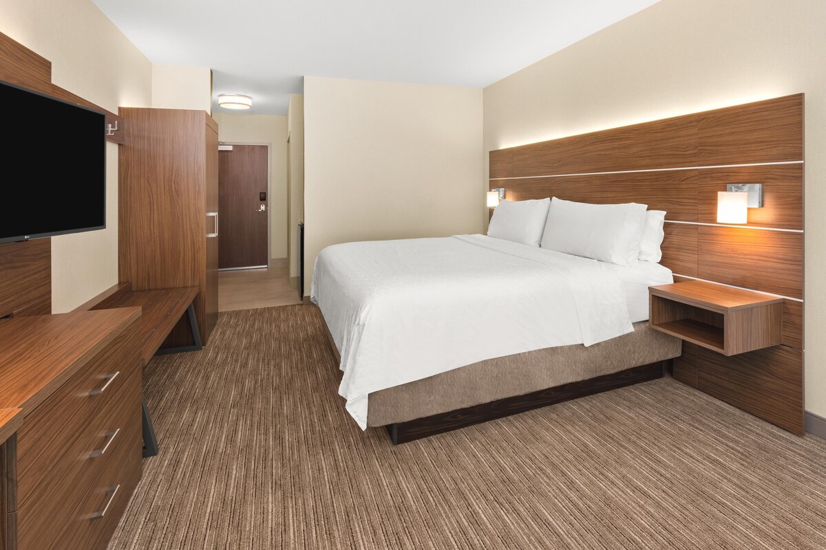 A hotel room with a bed, a TV, a desk, and a wardrobe.