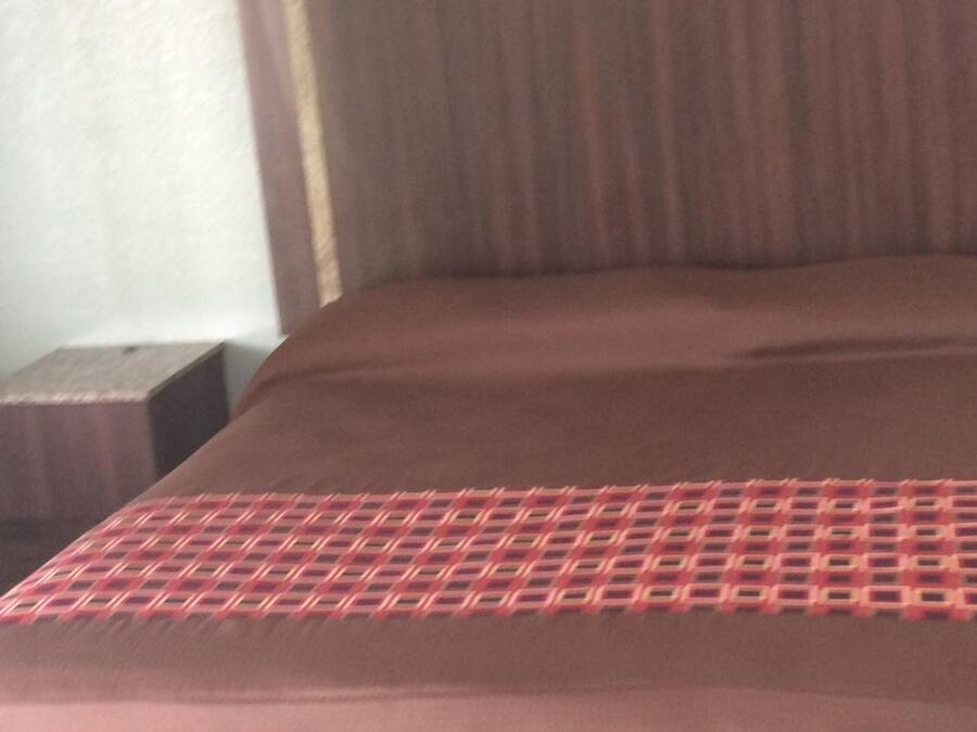 Un letto con una testiera marrone e una coperta a motivi.