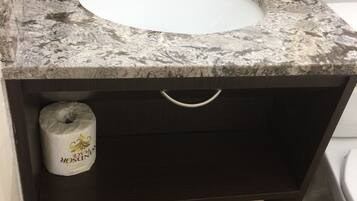 Een badkamer met een marmeren wastafel, een toiletrolhouder en twee handdoeken.