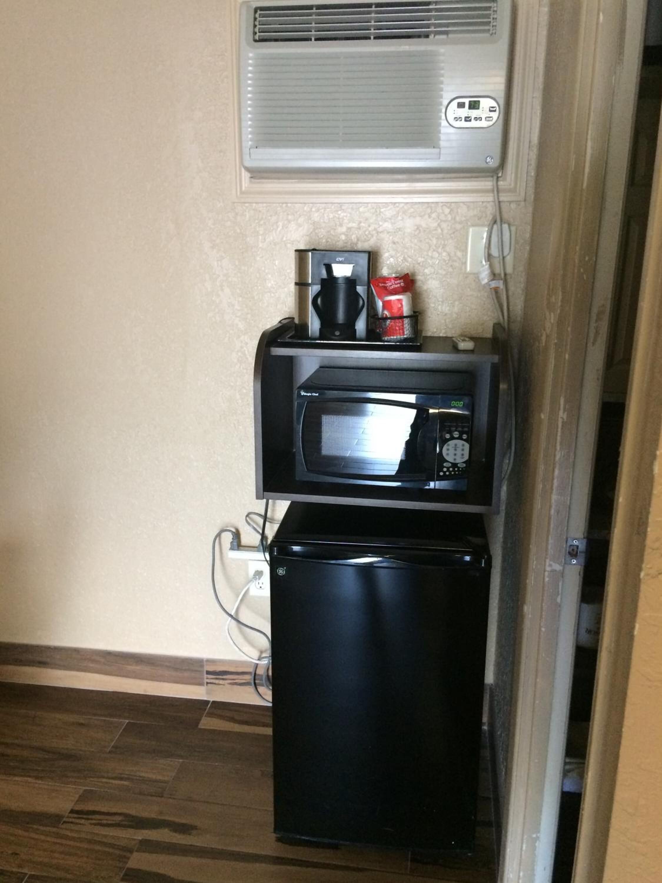 Een kleine keuken met een magnetron, koffiezetapparaat en een koelkast.