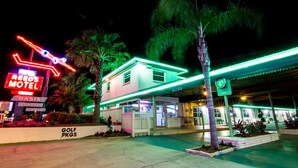 A motel with neon signs, a golf course sign, and a clock. - Budget Inn Of Avon Park (Avon Park)