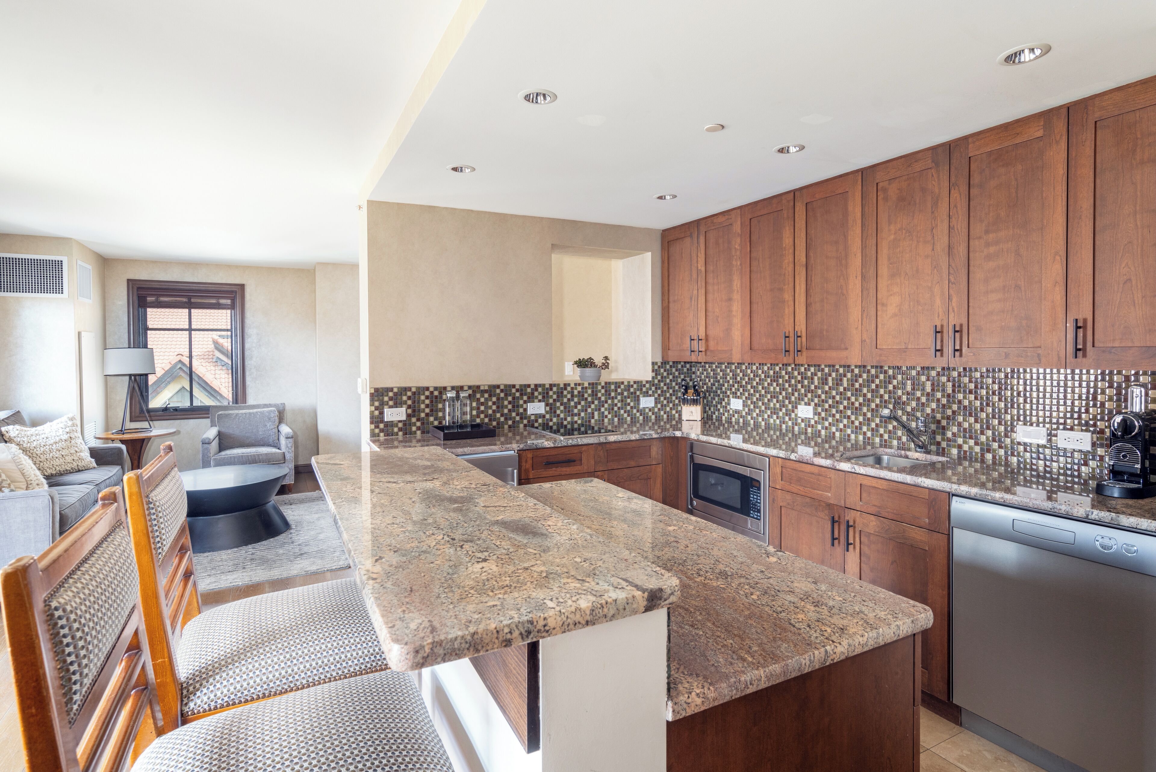 A modern kitchen with granite countertops, wooden cabinets, and a built-in dishwasher.