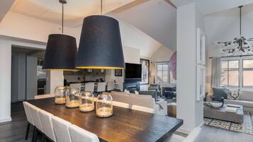 A modern dining area with a dark wooden table, multiple chairs, and two large pendant lights.
