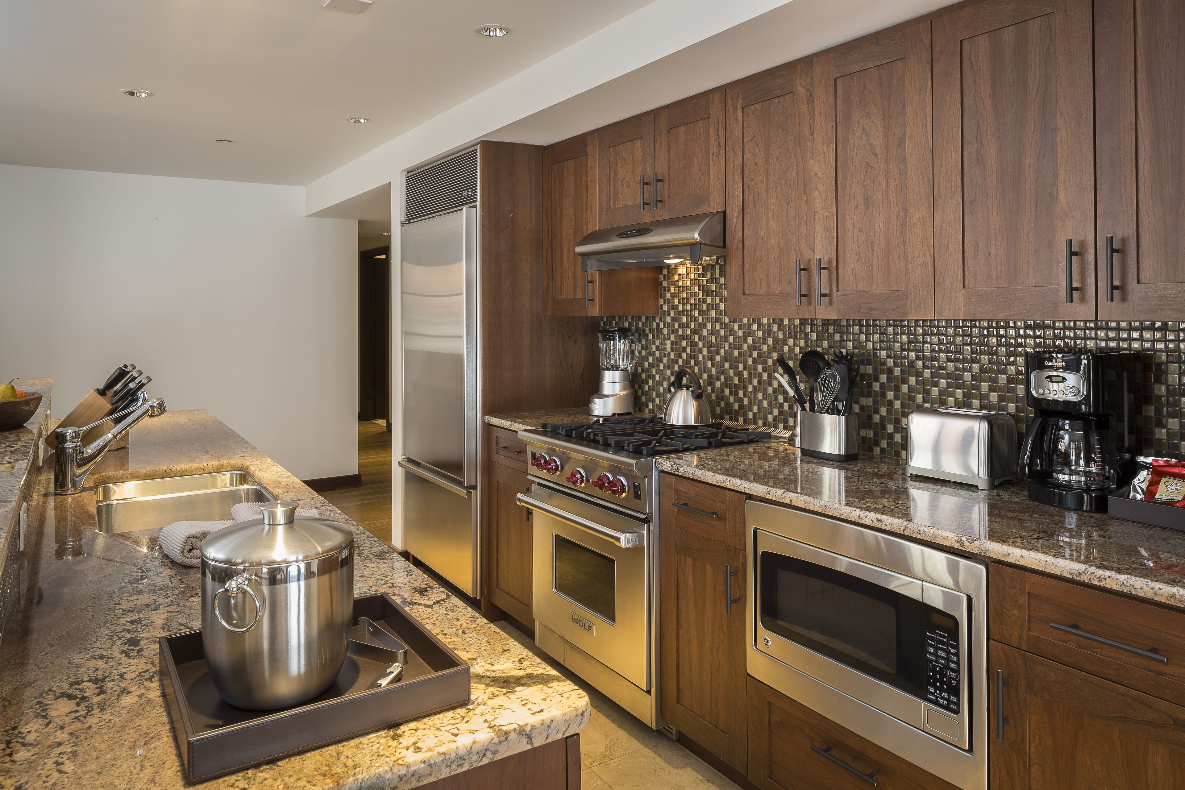 A modern kitchen with stainless steel appliances, wooden cabinets, and a granite countertop.