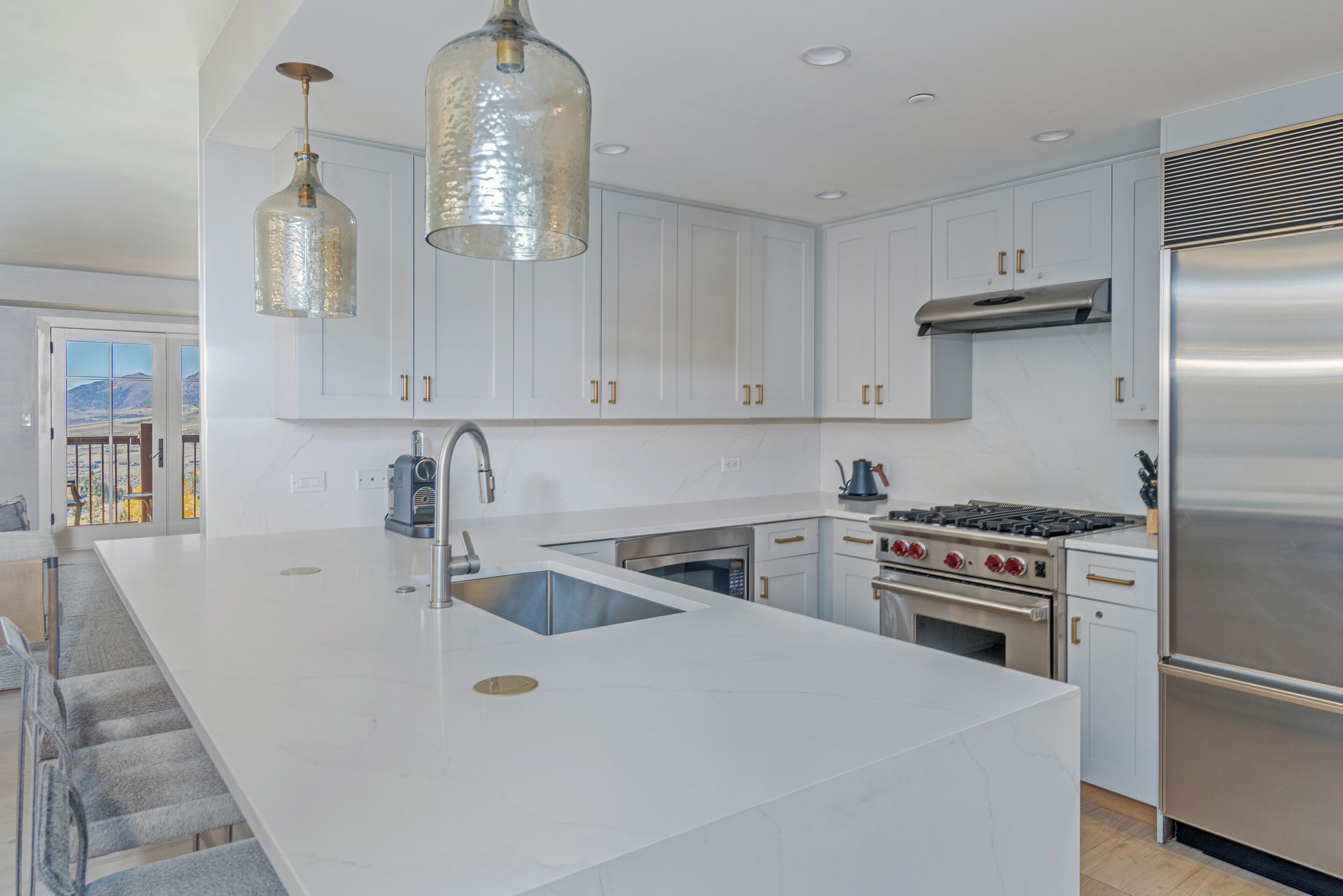 A modern kitchen with white cabinets, stainless steel appliances, and a large island with a sink.