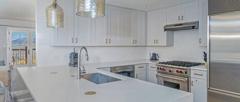 A modern kitchen with white cabinets, stainless steel appliances, and a large island with a sink.