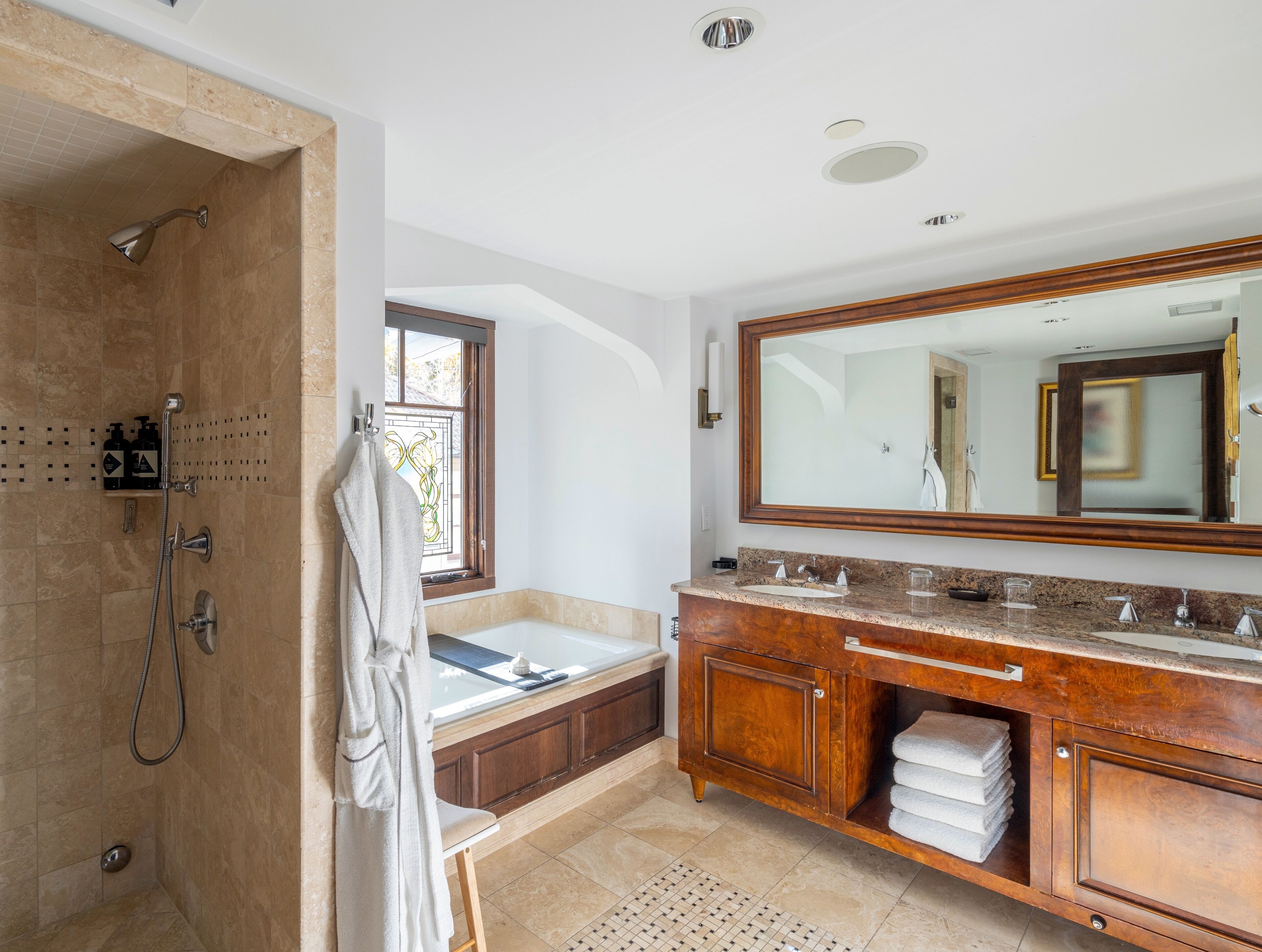 A modern bathroom with a walk-in shower, a large vanity with a mirror, and a bathtub.