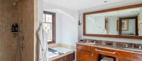 A modern bathroom with a walk-in shower, a large vanity with a mirror, and a bathtub.