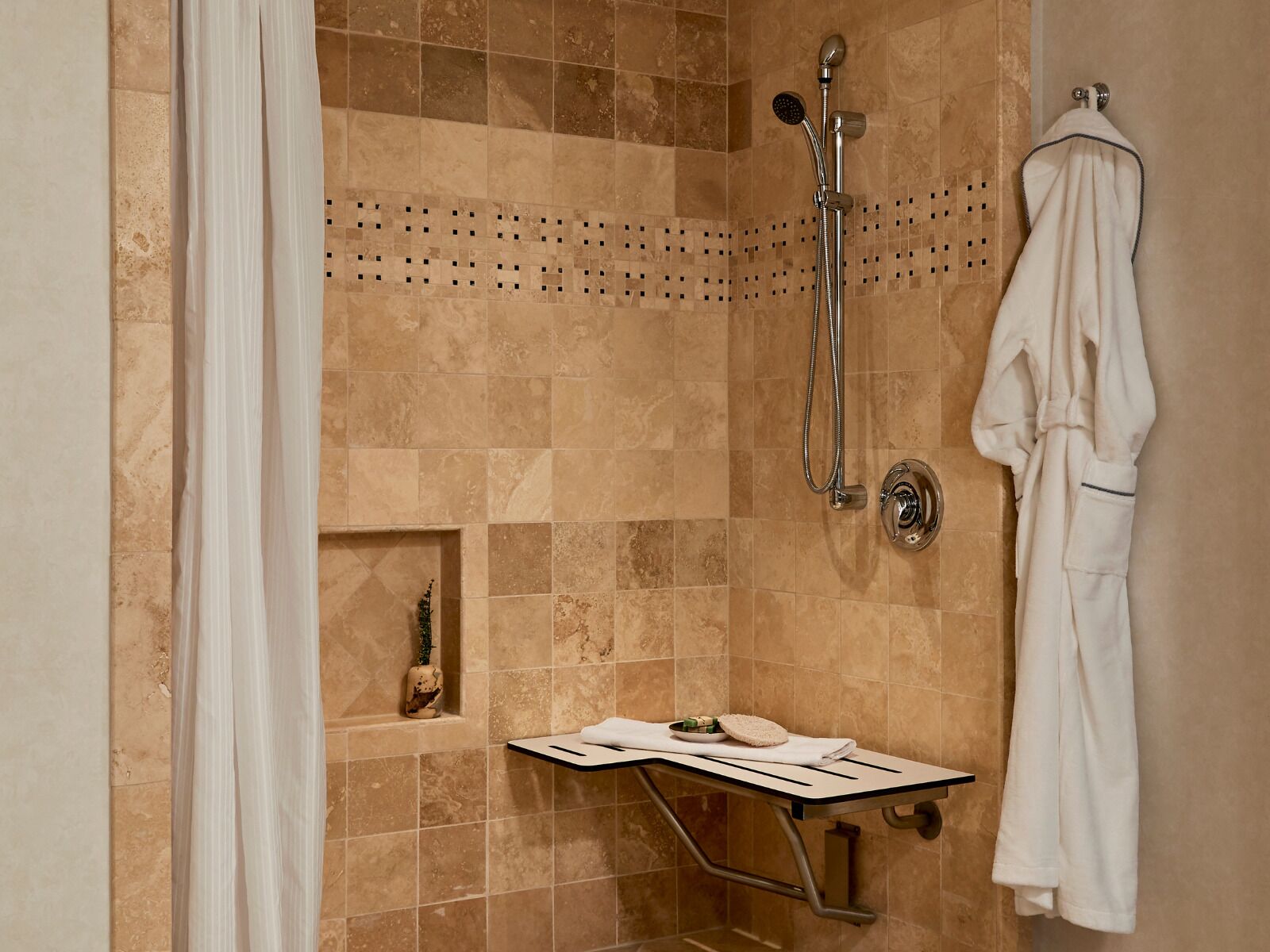 A shower area with a handheld showerhead, a wall-mounted showerhead, and a towel rack with a white robe.