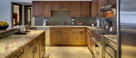 A modern kitchen with wooden cabinets, a granite countertop, stainless steel appliances, and a tiled backsplash.