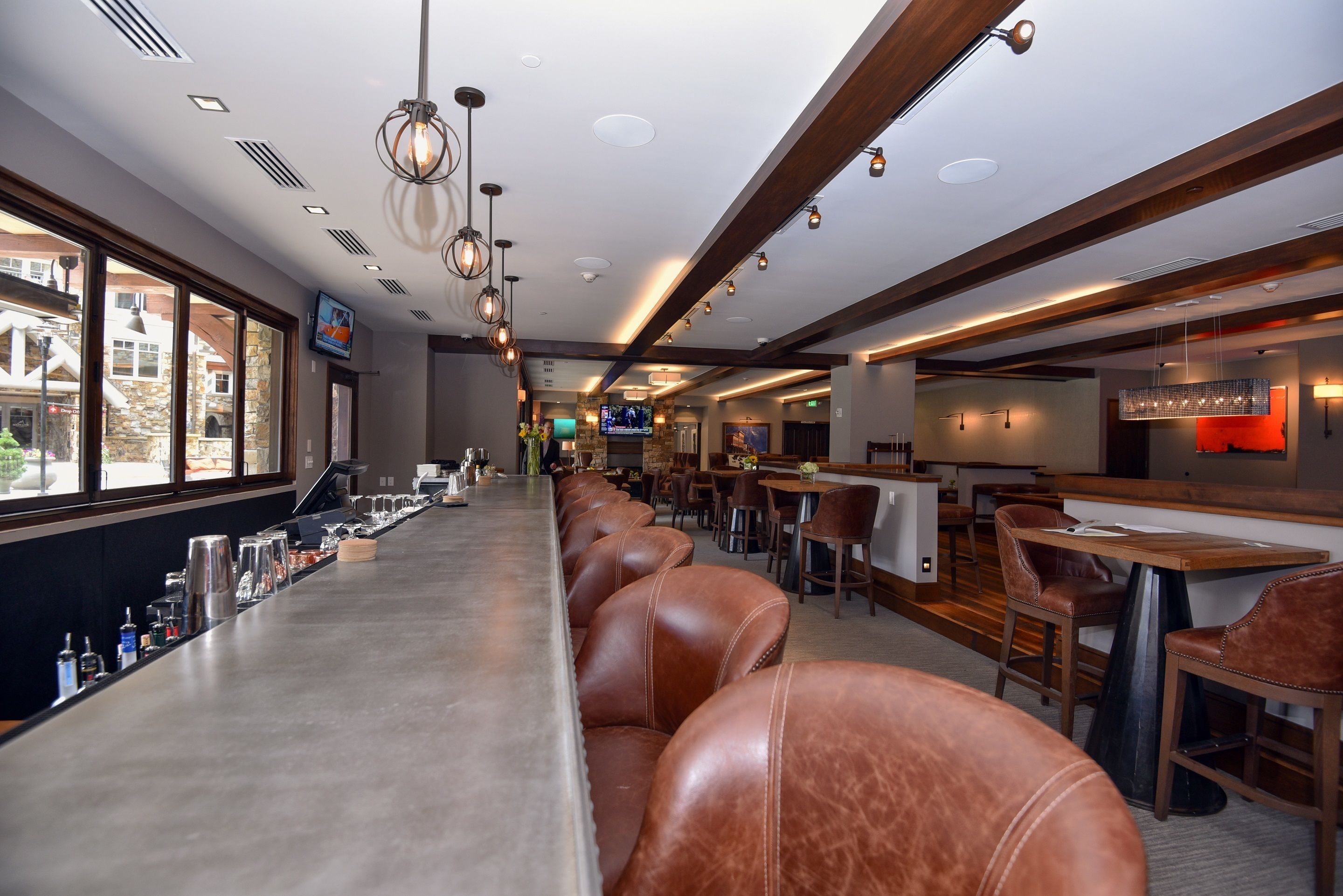 A bar area with leather seating, a long counter, and a television screen.