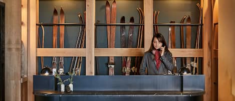 A reception desk with skis mounted on the wall behind it.