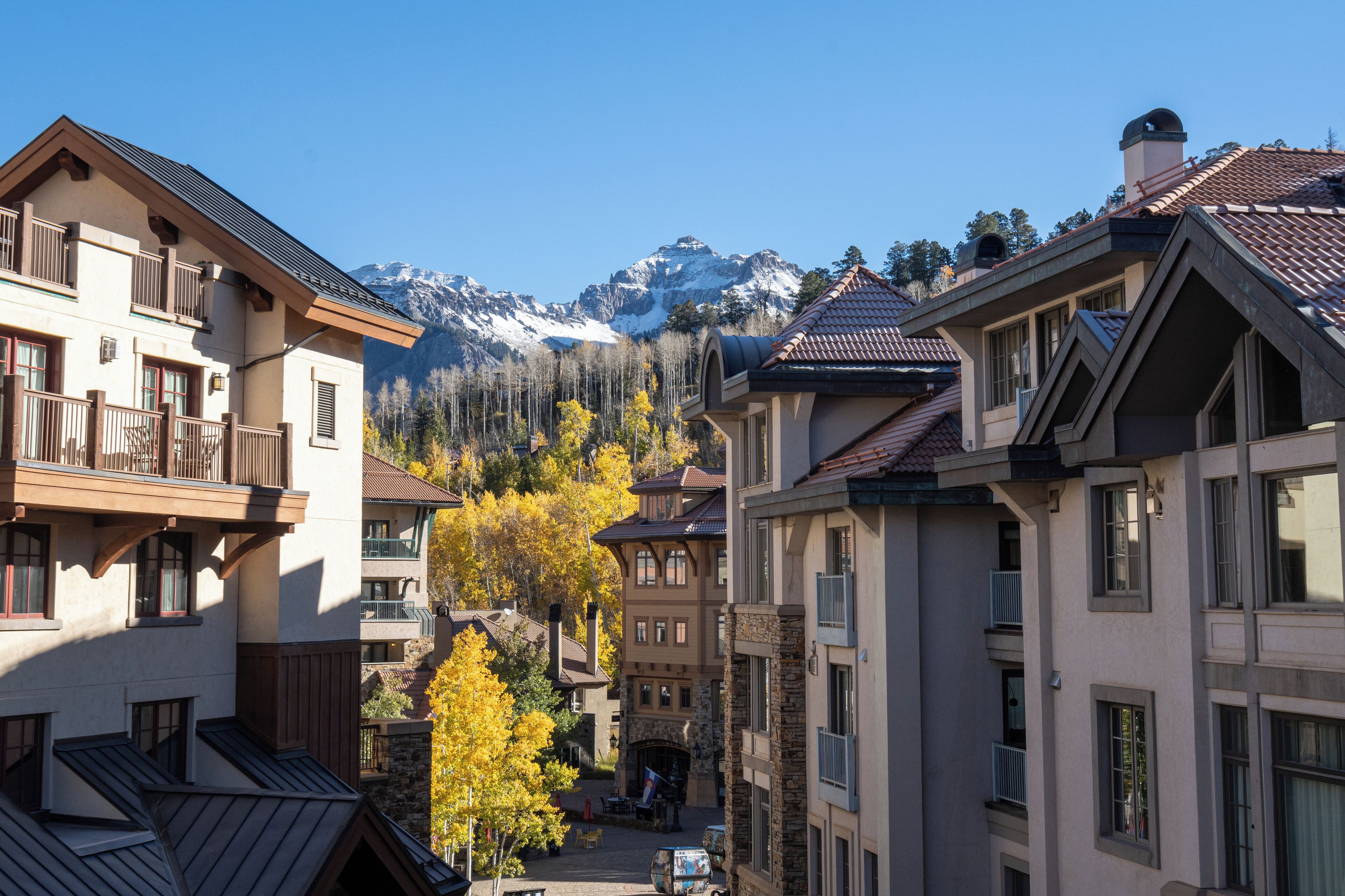 A multi-story building with balconies, a central courtyard, and a mountain backdrop.