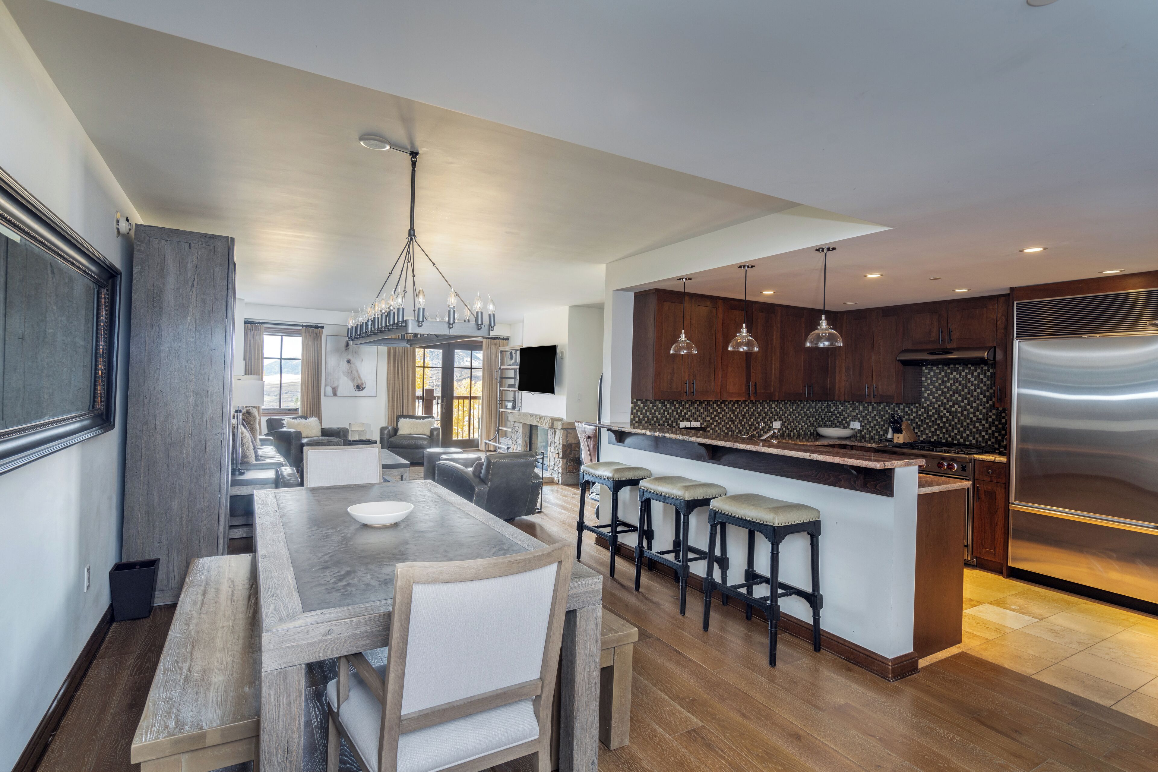 A modern kitchen with a central island, bar stools, and stainless steel appliances.