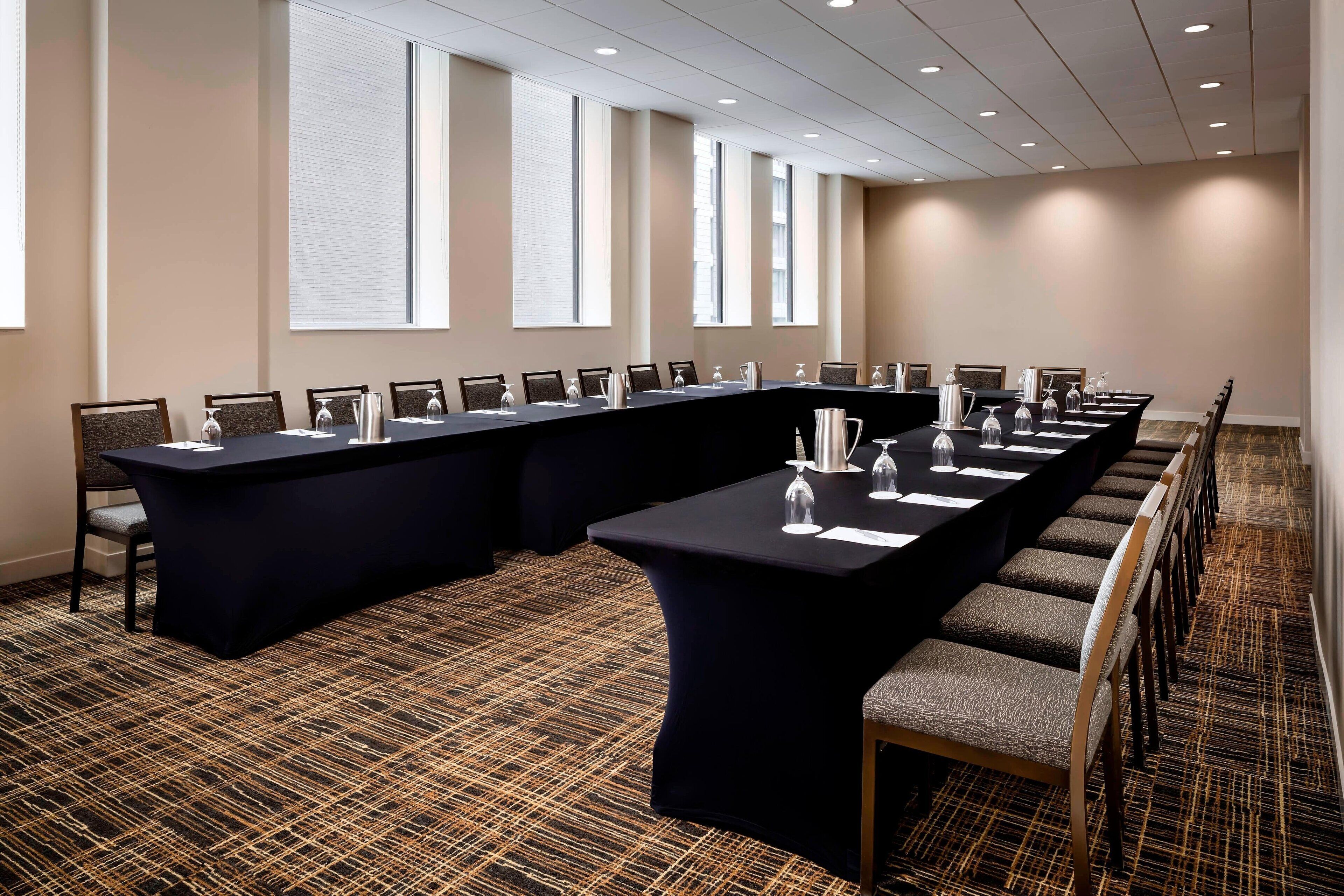 Un salón de conferencias con una mesa larga, sillas y suelo alfombrado.