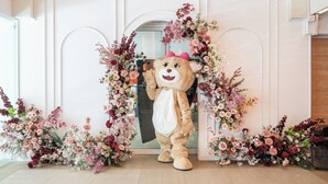 Una persona travestita da orso davanti a un arco fiorito.
