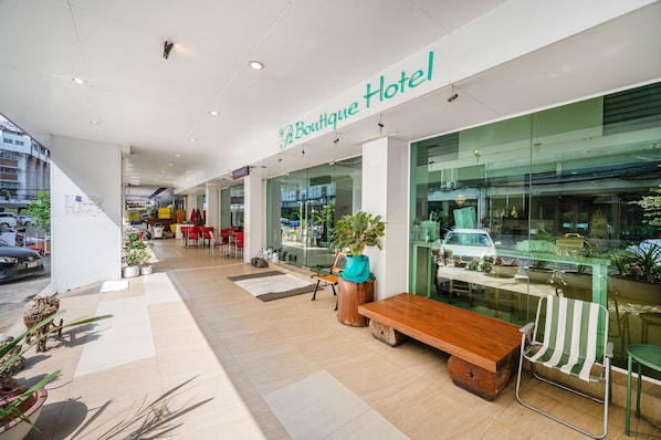 A boutique hotel with a modern interior, featuring a wooden bench and potted plants.