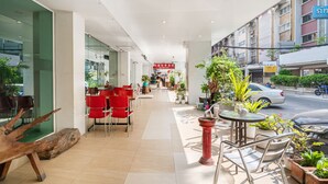 Una hall d'albergo moderna con poltrone rosse e piante in vaso.