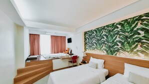 Camera d'albergo con due letti, una scrivania, una sedia, una televisione e un grande murale.