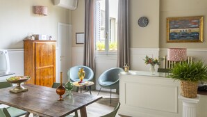 A dining area with a wooden table, two blue chairs, a cabinet, and a window with curtains. - Residenza Della Signoria (Florence)