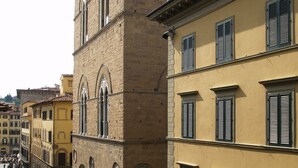 A historic building with arched windows and a clock, located in a busy urban area with pedestrians. - Residenza Della Signoria (Florence)