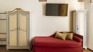 A living room with a red sofa, a television mounted on the wall, and a cabinet. - Residenza Della Signoria (Florence)
