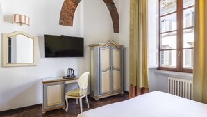 A hotel room with a bed, a desk with a chair, a television, a wardrobe, and a window with curtains. - Residenza Della Signoria (Florence)