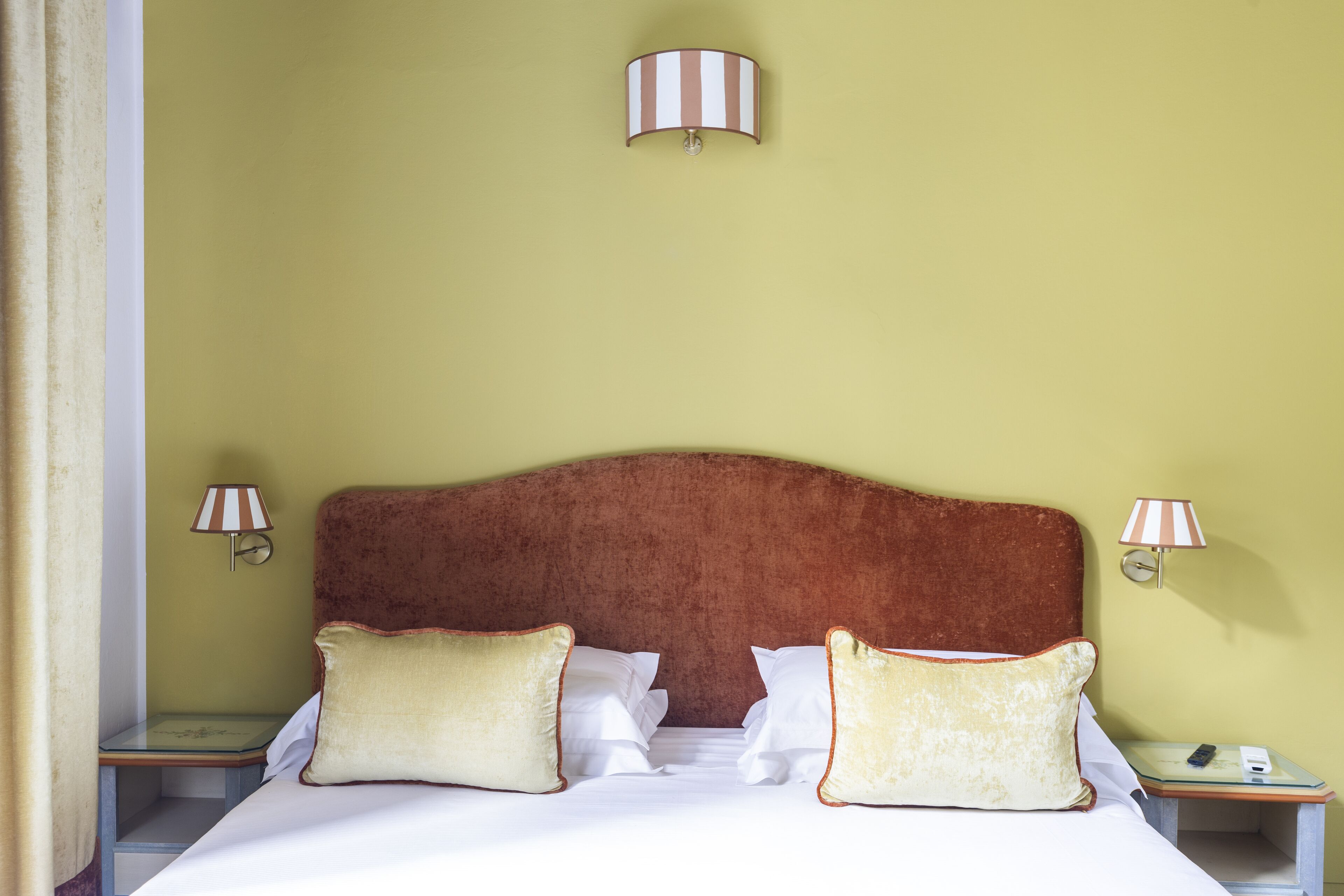 A neatly made bed with two pillows, a wooden headboard, and two bedside lamps on either side.