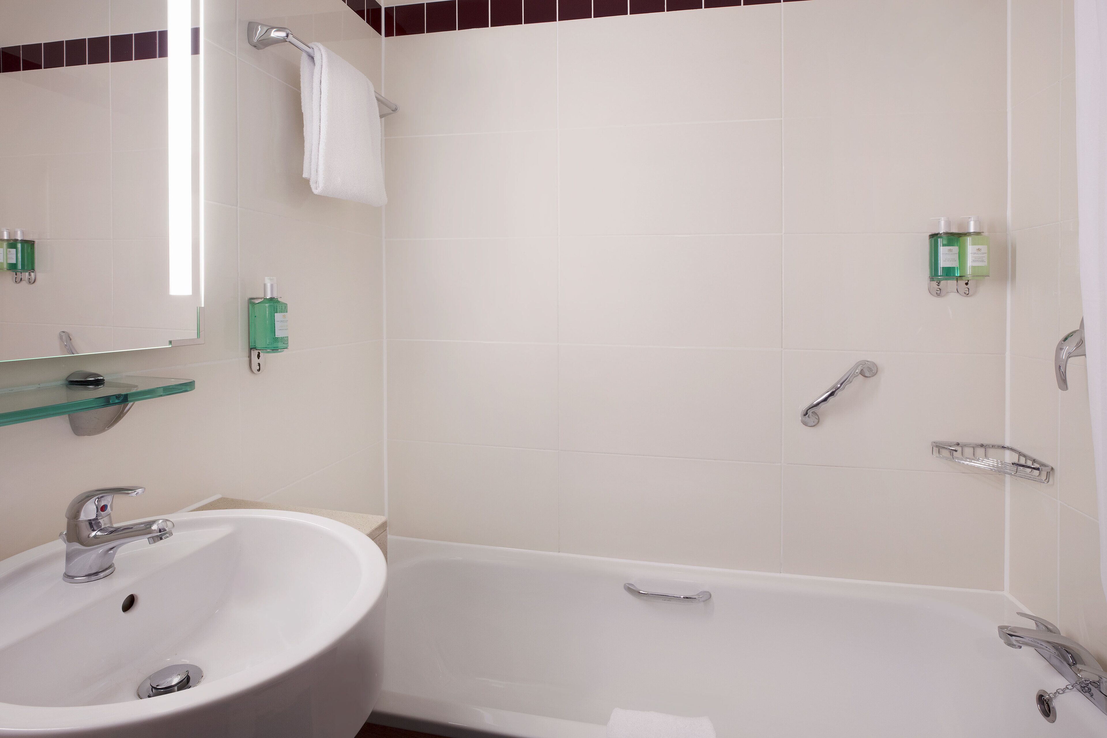 Un baño con un lavamanos blanco, un espejo, una bañera y un perchero para toallas.