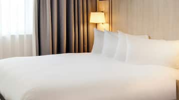 Una habitación de hotel con una cama grande, un cabecero de madera y dos lámparas de noche.