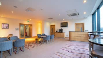 A hotel lobby with a reception desk, seating area, and a large window.