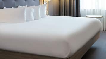 A neatly made bed with white linens, a tufted headboard, and a round bedside table.