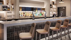 Un espace bar doté d’un long comptoir, de nombreux tabourets et d’une variété de bouteilles et de verres disposés sur des étagères.