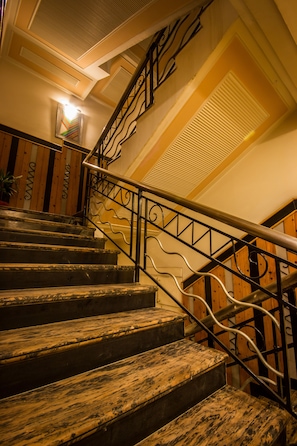 Eine Treppe mit Holzstufen und Metallgeländern, die zu einer Empore mit einer Lampe führt.