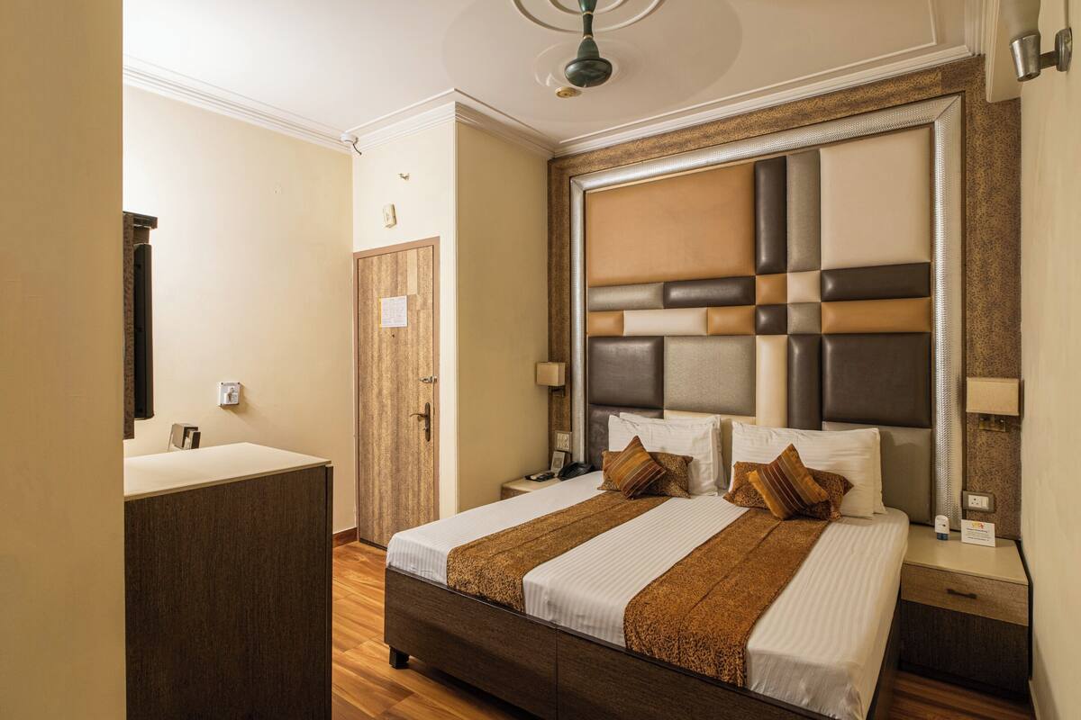 A bedroom with a large bed, bedside tables, a wardrobe, and a mirror.