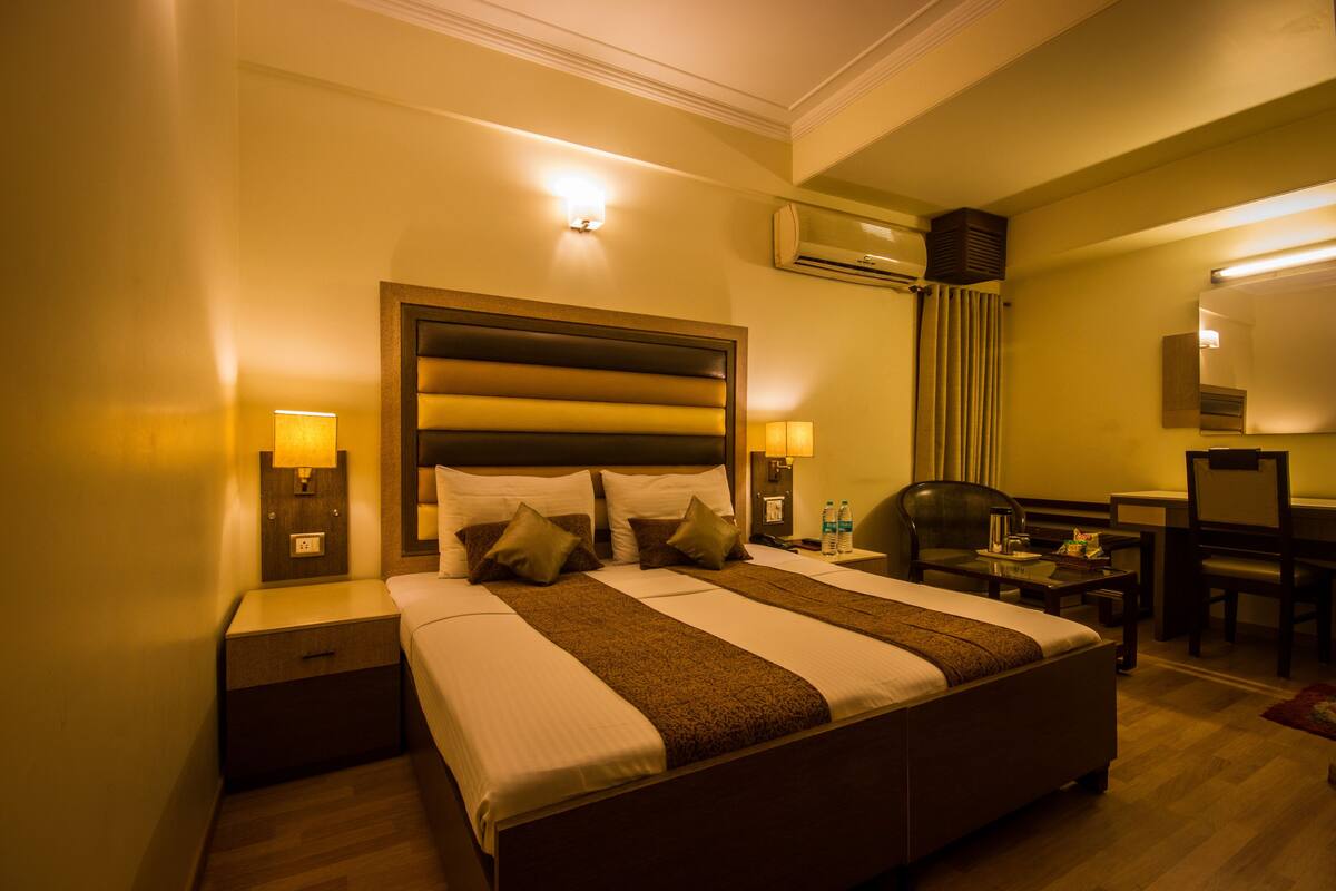 A hotel room with a large bed, bedside lamps, a desk, and a chair.