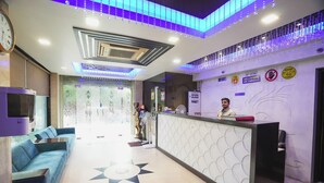Un'area reception di un hotel dal design moderno, con scrivania, angolo salotto e luci decorative a soffitto.