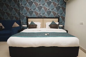 A neatly made bed with a patterned bedspread, a headboard, and two pillows. - Hotel B Continental (New Delhi)