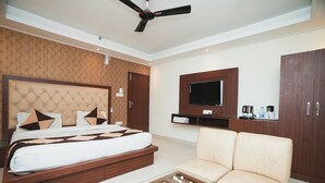 Una camera da letto moderna con un letto grande, un divano, una TV a parete e una ventola a soffitto.